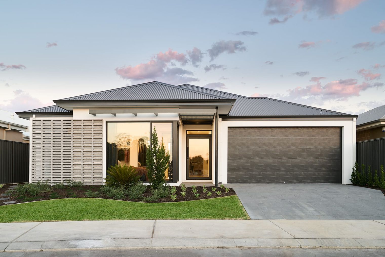 Modern single-story house with white facade, large windows, sleek roof, and landscaped front yard.