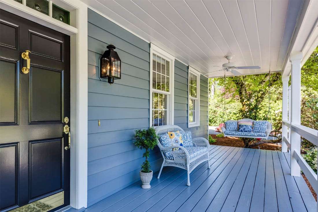Inviting front porch with cosy seating, swing, and pastel decor.
