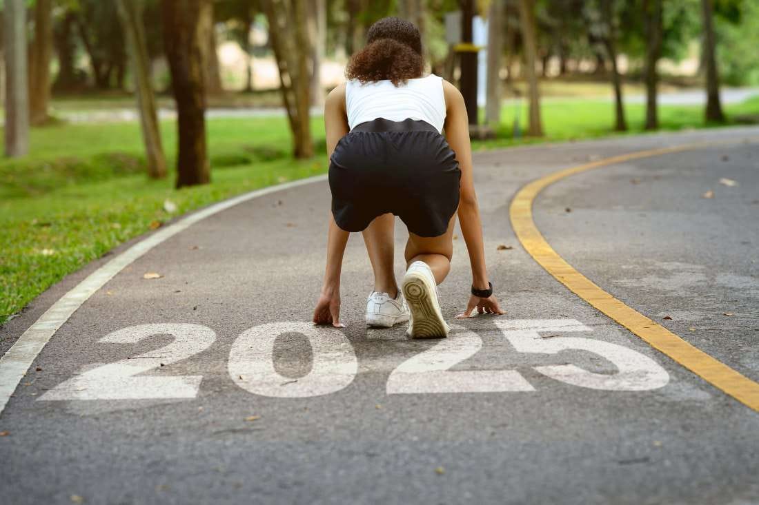 Young female athlete ready to sprint on track, aiming for goals marked by 2025.