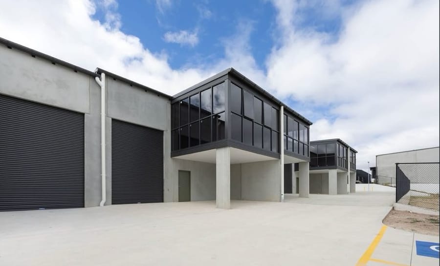 Completed industrial warehouse unit at Hume ACT with roller door and glazed first-floor office